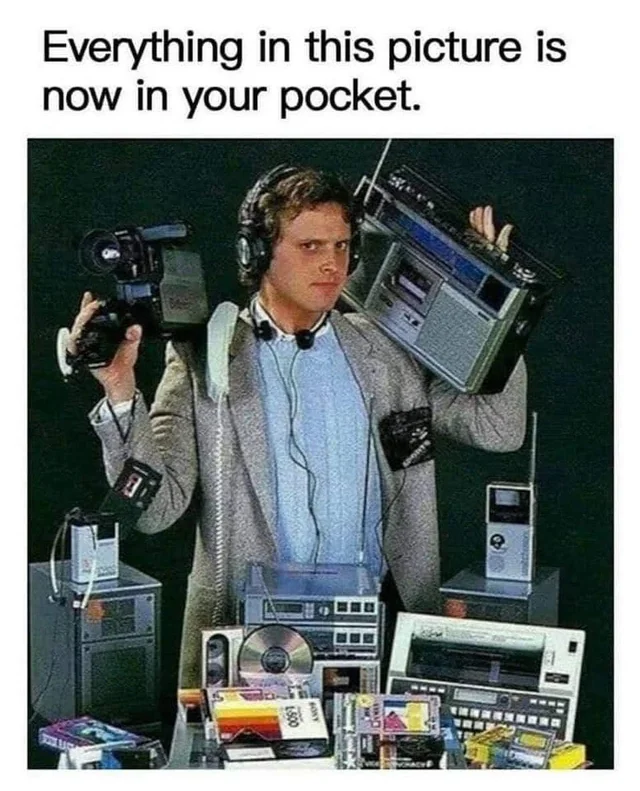 Man from the 1980s holding a boombox and camcorder, surrounded by gadgets. Caption: Everything in this picture is now in your pocket.